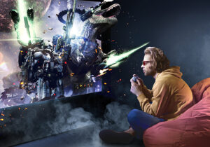 Young man sitting on beanbag chair playing video games, with video game monster coming out of the tv.