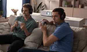 Two young men playing video games on a couch, looking at a screen.
