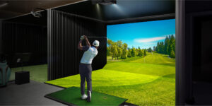 Man taking a golf swing against a screen displaying a virtual golf course.