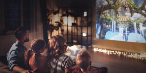 A family watching a movie on a projector in a dark living room.