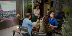 Four friends drinking wine on a patio with a projector screen showing a movie.